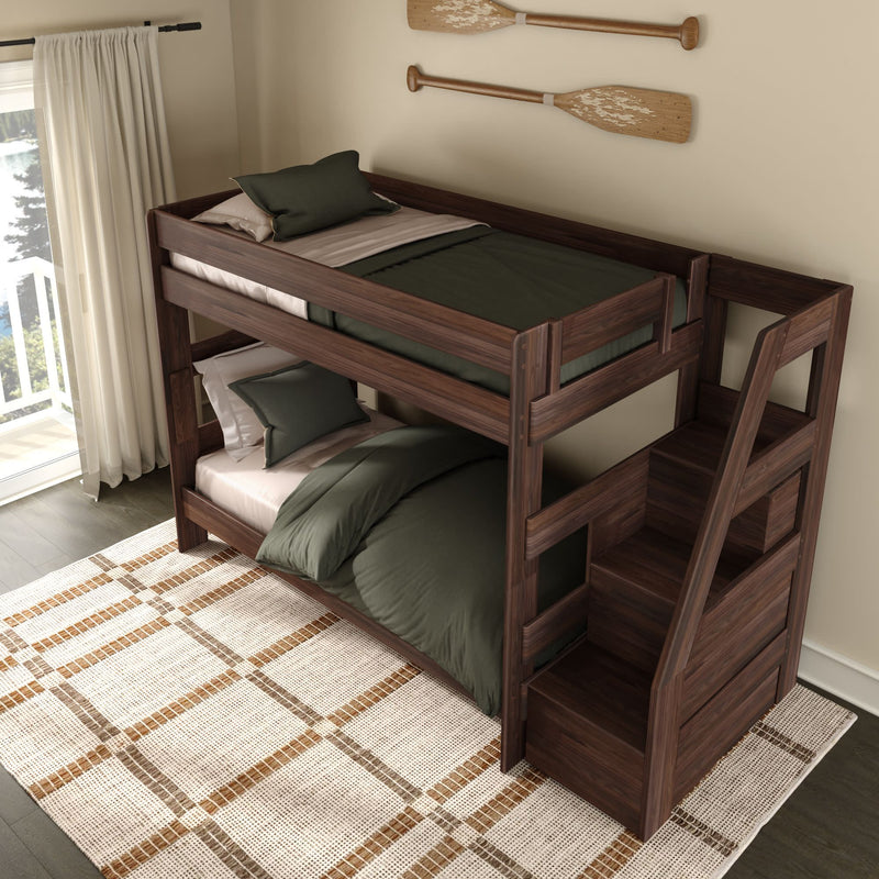 Wooden twin-over-twin bunk bed with built-in storage staircase in dark walnut finish, green bedding and pillows, rustic oar wall decor, cream curtains and patterned area rug in a bright kids' bedroom