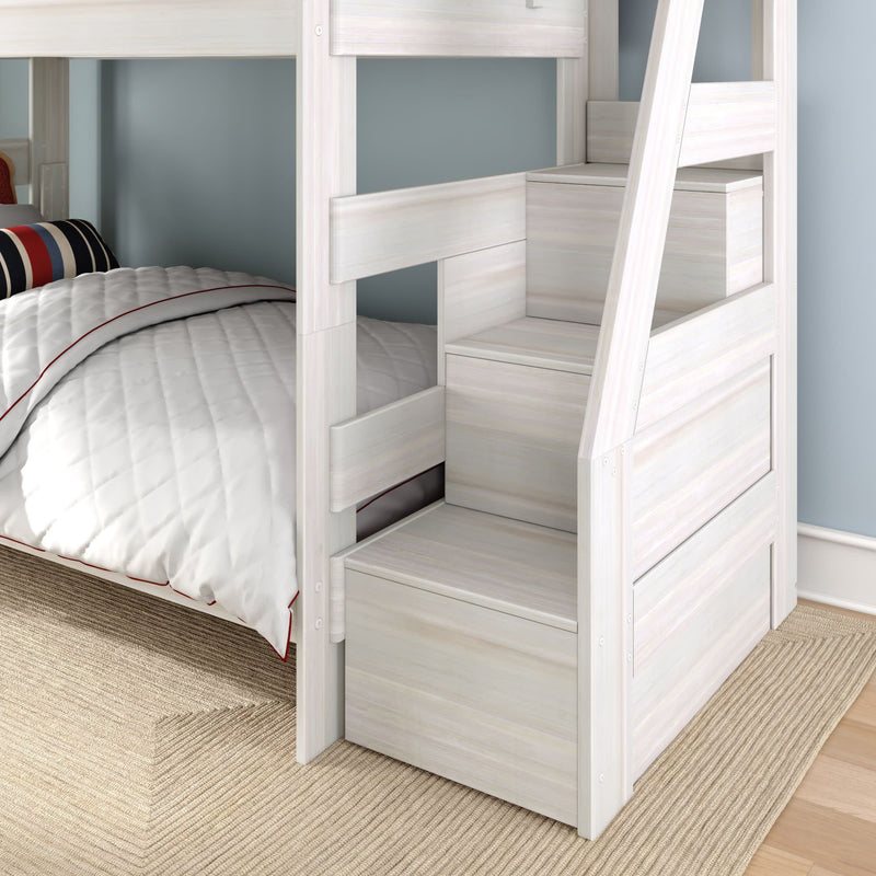 Whitewashed twin-over-twin bunk bed with staircase and built-in storage drawers, white quilted bedding and navy-red striped pillow in a space-saving kids' bedroom