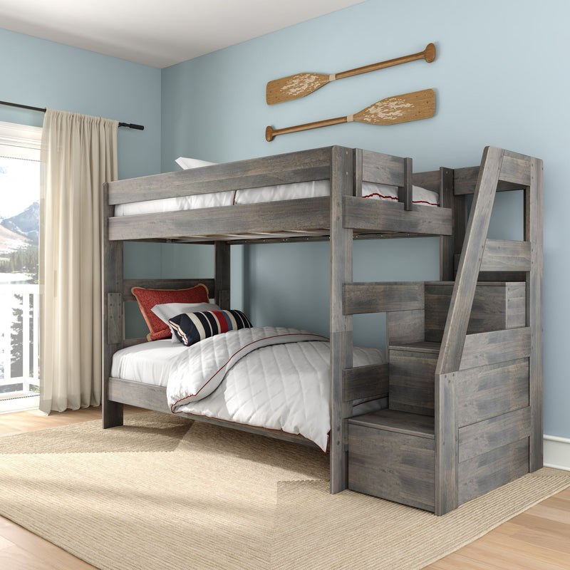 Gray wooden bunk bed with built-in ladder storage, white quilted bedding and navy-red striped pillows in a coastal kids' bedroom with light blue walls and decorative wooden oars.