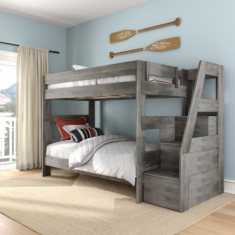 Gray rustic wood twin-over-twin bunk bed with built-in staircase and storage drawers in coastal bedroom, light blue walls, white quilted bedding with navy and red striped pillows, wooden oar wall decor and natural area rug