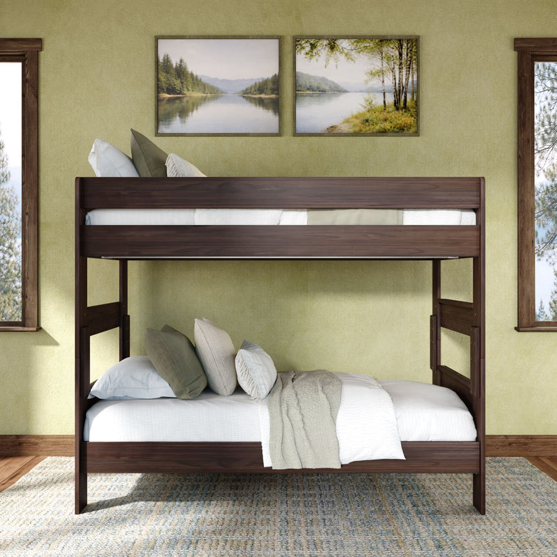 Dark wood bunk bed in a rustic bedroom with green walls, landscape wall art, white bedding and pillows, hardwood floors and natural light