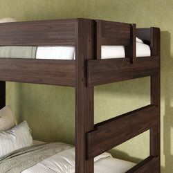 Dark walnut wooden twin-over-twin bunk bed with safety guardrails and ladder, styled with white bedding against a green textured wall