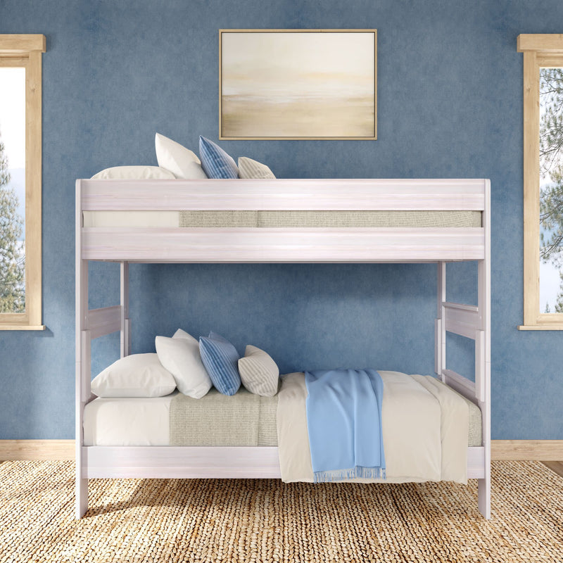 White wooden bunk bed with blue throw and striped pillows in a coastal-style children’s bedroom with textured blue walls, woven jute rug, framed art and natural light through windows
