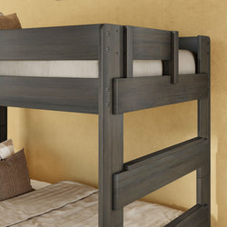 Dark gray solid wood twin-over-twin bunk bed with safety guardrails, beige bedding and pillows in a children's bedroom