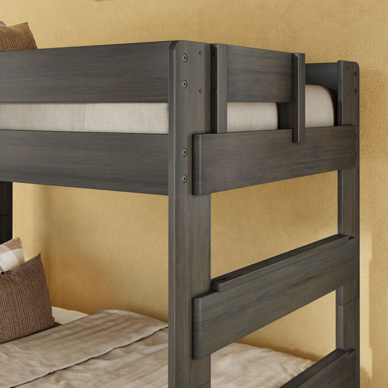 Dark gray solid wood twin-over-twin bunk bed with safety guardrails, beige bedding and pillows in a children's bedroom