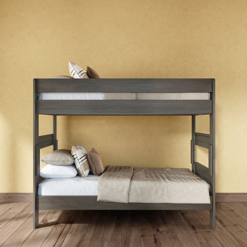 Modern gray wooden bunk bed with neutral bedding and plaid decorative pillows against a warm yellow wall on hardwood floor, space-saving bedroom furniture