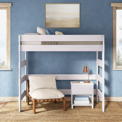 White wooden twin loft bed with mattress, cozy lounge chair and white nightstand with copper lamp against blue accent wall — modern small-space bedroom furniture and reading nook