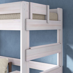 Close-up of whitewashed wooden bunk bed ladder and guardrails with beige woven mattress and blue textured wall, modern twin bunk bed frame for children's bedroom