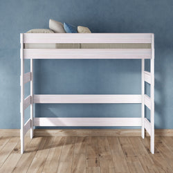 White wooden loft bed with ladder and guardrails, modern space-saving raised bed frame with pillows against a blue textured wall on hardwood floor