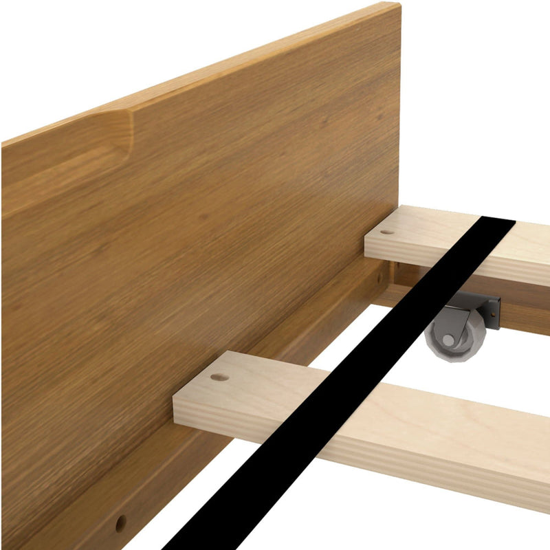 Close-up of wooden bed frame assembly with oak-finish headboard, pine slats, black central support beam and caster wheel.