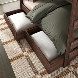Under-bed storage drawers in walnut bunk bed with green bedding and white pillows on patterned rug, space-saving bedroom organizer