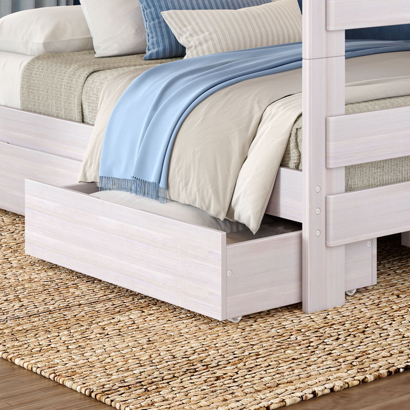 White wooden bunk bed with trundle drawer styled with beige bedding, striped pillows and a light blue throw on a woven jute rug