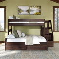 Dark wood twin-over-full bunk bed with staircase and storage, cozy neutral bedding against a green accent wall, framed lake landscape prints and large windows with pine tree views