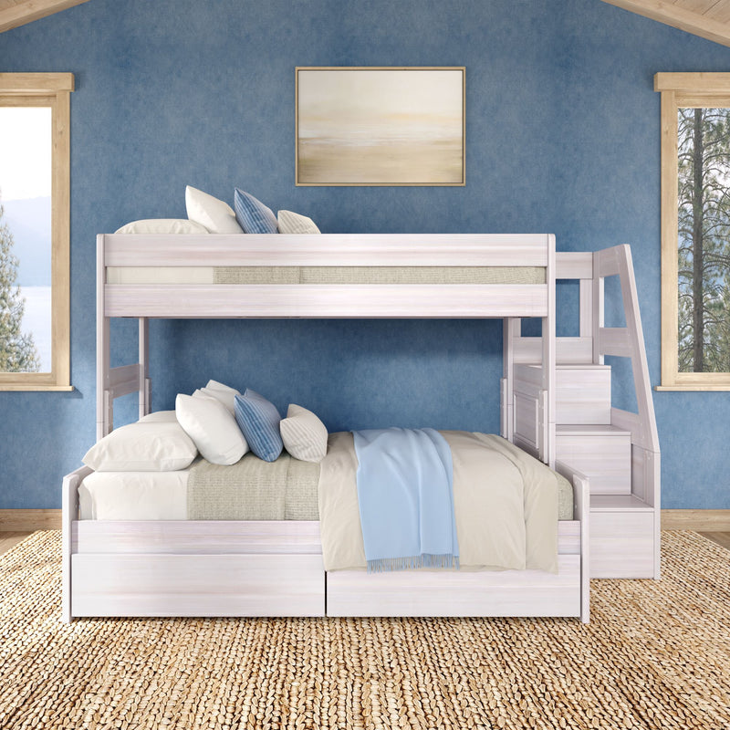 White wooden bunk bed with beige bedding and blue throw against a blue textured wall with framed coastal art, natural wood windows, and woven jute rug