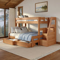 Solid wood bunk bed with staircase storage and pull-out trundle drawers in a cozy cabin bedroom with blue linens, layered pillows and large windows overlooking a forested lake