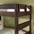 Dark walnut solid wood bunk bed with integrated ladder and safety guardrails, styled with neutral bedding against a textured green bedroom wall