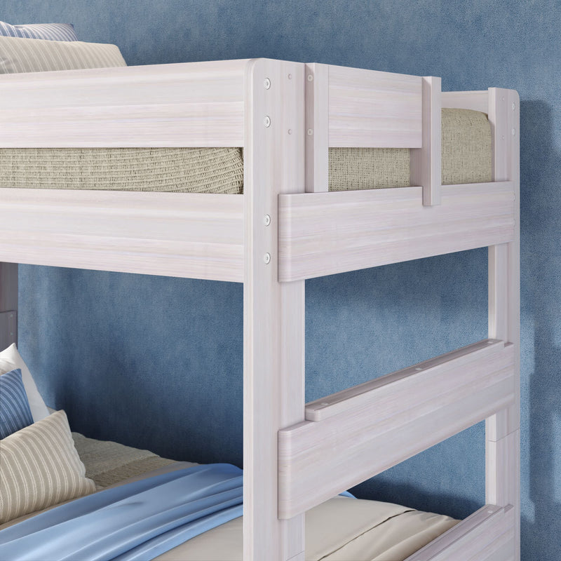 White painted wooden twin bunk bed with guard rails, beige mattresses and blue bedding against a textured blue wall — modern children's bedroom furniture