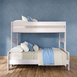 White wooden twin-over-full bunk bed with beige linens, blue throw blanket and striped accent pillows against a blue textured wall on hardwood floor