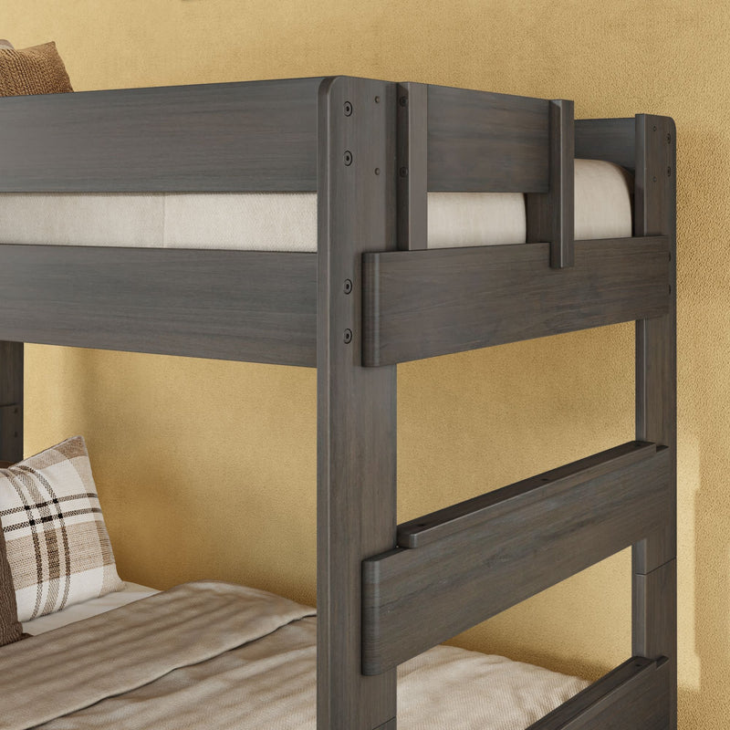 Gray wooden bunk bed corner with safety guardrails, beige mattress and plaid pillow against a textured yellow wall — modern rustic bedroom furniture