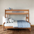 Modern wooden bunk bed with blue linens and white pillows on hardwood floor in a minimalist bedroom