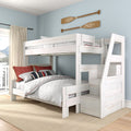 Whitewashed wooden twin-over-full bunk bed with built-in staircase storage, white quilted bedding and red accent pillows in a coastal kids bedroom with oar wall decor and large window