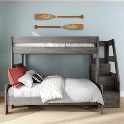 Gray wooden bunk bed with staircase, white quilted bedding and red accent pillows beneath nautical wooden oar wall decor in a coastal-style kids bedroom