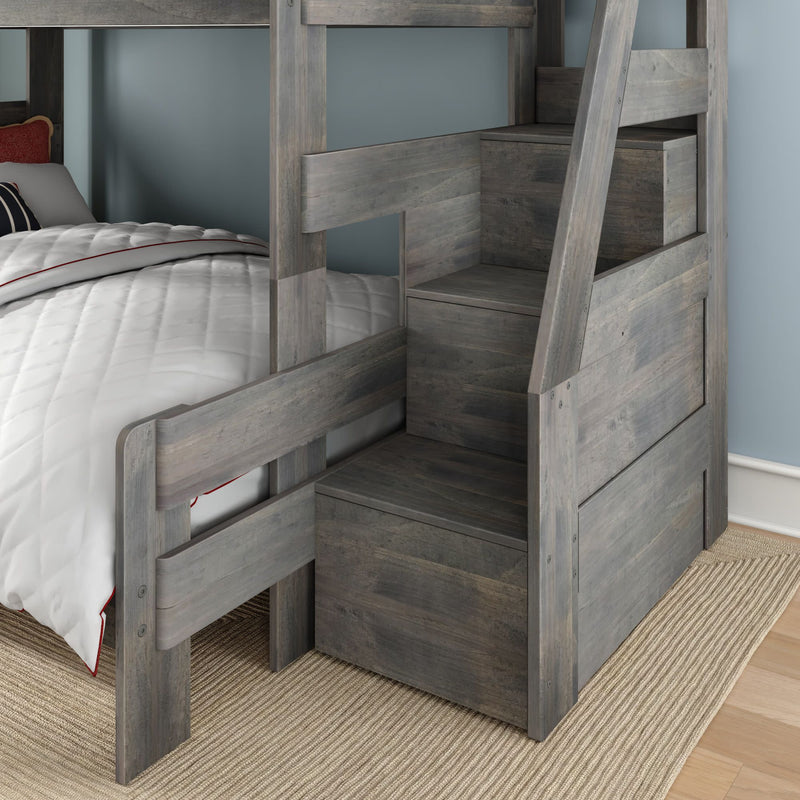 Gray wooden bunk bed with built-in storage staircase and drawers, white quilted bedding on lower bunk in a space-saving kids' bedroom with blue wall and woven rug
