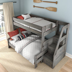 Gray wooden twin-over-full bunk bed with built-in storage stairs and drawers, white quilted bedding, red accent pillows, and oar wall decor in a bright coastal kids' bedroom