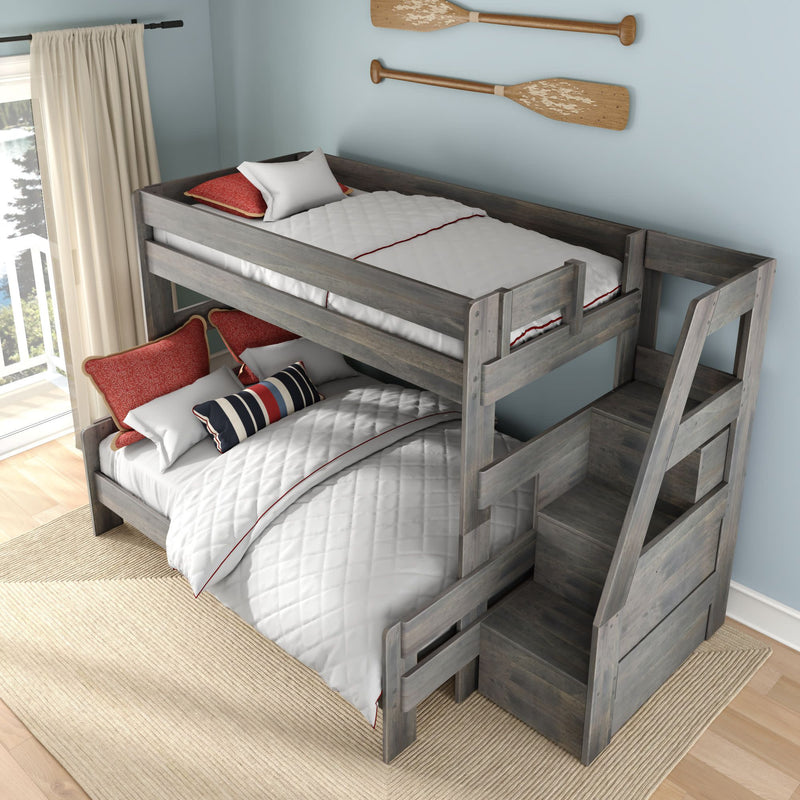 Gray wooden twin-over-full bunk bed with built-in storage stairs and drawers, white quilted bedding, red accent pillows, and oar wall decor in a bright coastal kids' bedroom