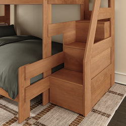 Space-saving wooden bunk bed with built-in storage stairs and drawers, lower bed with dark gray bedding on woven rug