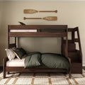 Wooden twin-over-full bunk bed with built-in stair storage, dark green bedding and decorative wooden oars on wall in modern rustic bedroom