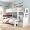 White wooden twin-over-full bunk bed with storage staircase in light-blue coastal bedroom, quilted bedding, red accent pillows and paddle wall decor
