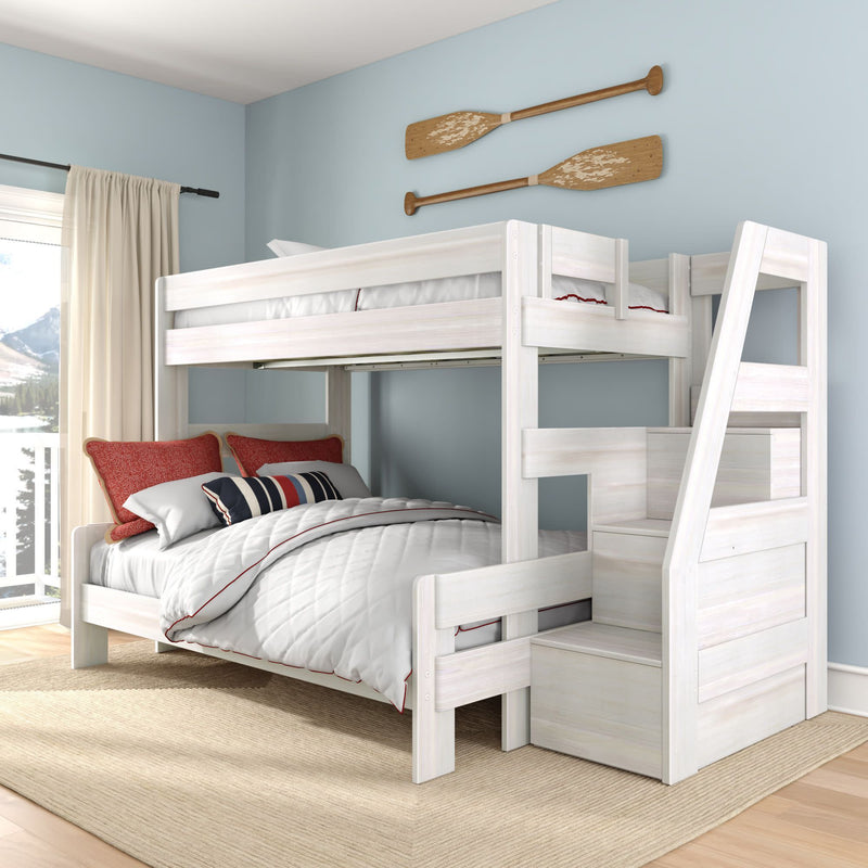 White wooden twin-over-full bunk bed with storage staircase in light-blue coastal bedroom, quilted bedding, red accent pillows and paddle wall decor