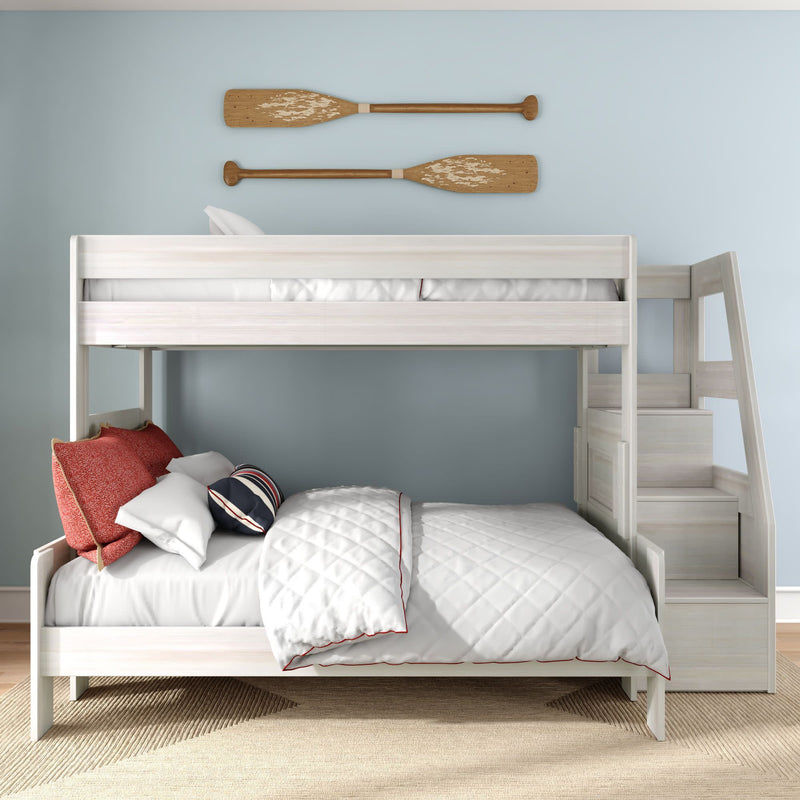 White wooden bunk bed with staircase in coastal kids bedroom, light blue wall with wooden oar decor, white quilted bedding and red accent pillows