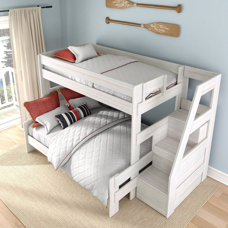 White wooden twin-over-full bunk bed with built-in storage stairs, quilted white bedding, red and striped accent pillows, oar wall decor and balcony sunlight in a coastal-style kids' bedroom
