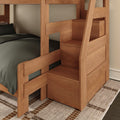 Solid wood twin-over-twin bunk bed with built-in storage stairs, natural wood finish, dark bedding and area rug in a space-saving kids' bedroom