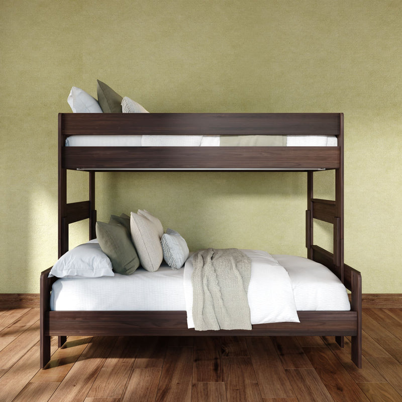 Dark wood twin-over-full bunk bed with white linens, layered pillows and beige throw against a green textured wall and hardwood floor