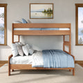 Twin-over-full wooden bunk bed with light wood frame, blue bedding and neutral pillows in bright coastal bedroom.