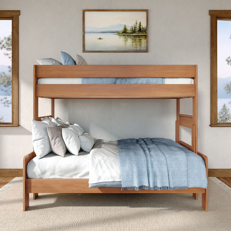 Twin-over-full wooden bunk bed with light wood frame, blue bedding and neutral pillows in bright coastal bedroom.