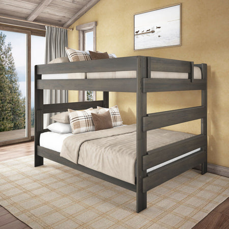 Gray wooden full-over-full bunk bed in rustic cabin bedroom with neutral bedding, plaid pillows, wood-beam ceiling and large window overlooking forest