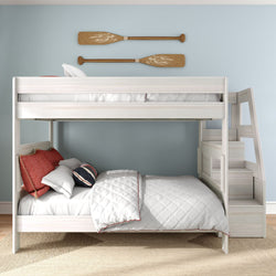 White wooden bunk bed with built-in staircase in a coastal kids' bedroom, light blue wall with wooden oars, white quilted bedding and red accent pillows