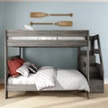 Gray wooden bunk bed with built-in stairs, white quilted comforter and red accent pillows in coastal kids' bedroom with rustic wooden oar wall decor