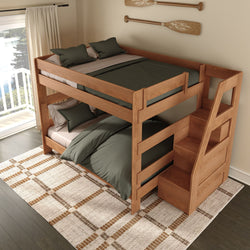 Solid wood twin-over-full bunk bed with built-in storage staircase and green bedding in a coastal-style bedroom with oar wall decor, large window overlooking a lake, patterned rug, and dark hardwood floor