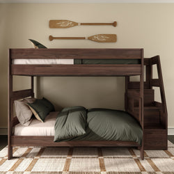 Dark walnut twin-over-full wooden bunk bed with built-in staircase and storage, olive green bedding, woven area rug and rustic oar wall decor in a neutral bedroom