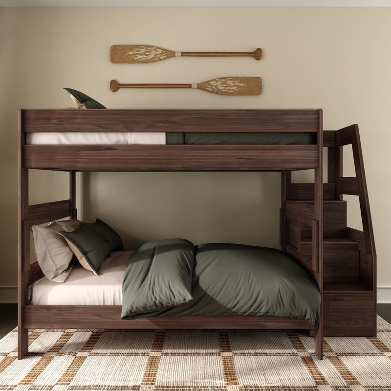 Dark walnut twin-over-full wooden bunk bed with built-in staircase and storage, olive green bedding, woven area rug and rustic oar wall decor in a neutral bedroom