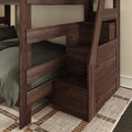 Dark walnut wooden bunk bed with built-in staircase storage drawers, green bedding and woven area rug in a modern bedroom
