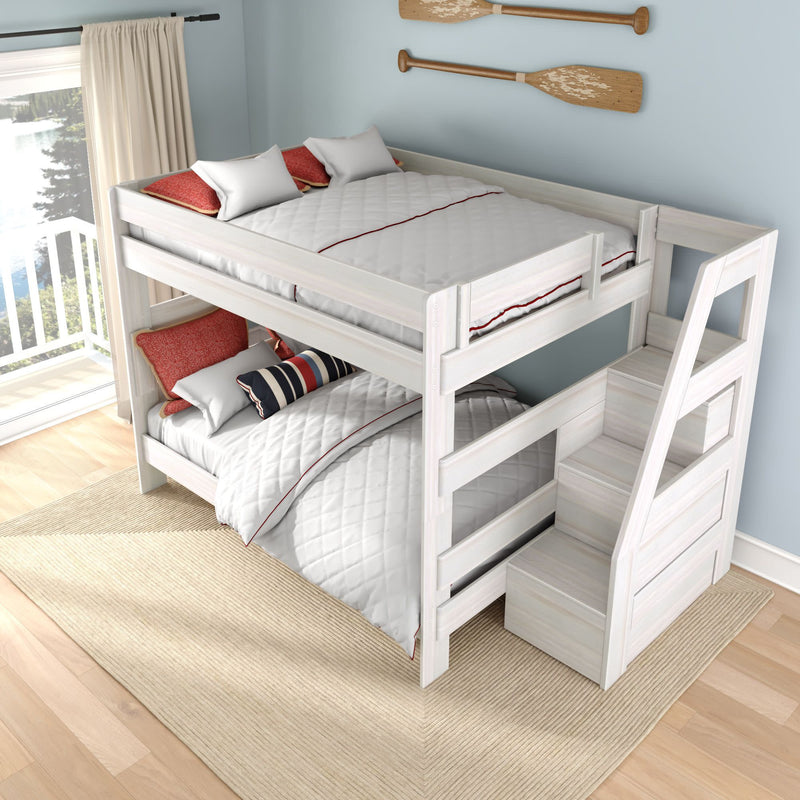 White wooden bunk bed with built-in staircase in coastal bedroom, white quilted bedding and red accent pillows, hardwood floor, rug and lake-view balcony