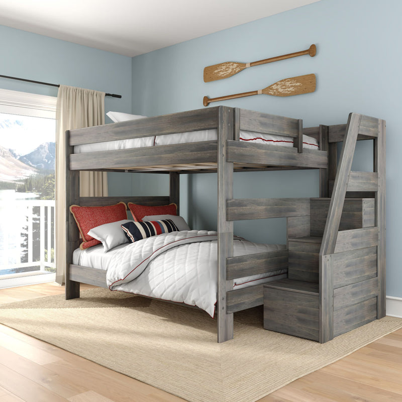 Grey wooden twin-over-full bunk bed with built-in storage stairs in coastal kids bedroom, white quilted bedding, red accent pillows, nautical paddle wall decor and lake view