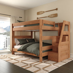 Solid wood twin-over-full bunk bed with storage stairs, green bedding, plaid rug and decorative oars in bright bedroom with balcony mountain-lake view
