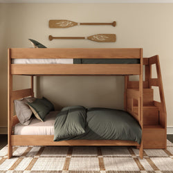 Wooden twin-over-full bunk bed with built-in storage stairs, green bedding and decorative oar wall art in a modern rustic kids' bedroom